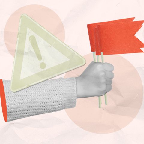 hand holding red flags and a warning sign